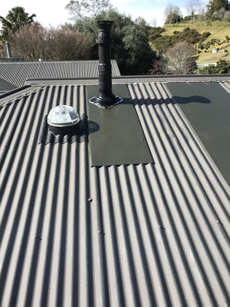 roof repairs on a grey roof with chimney and skylight